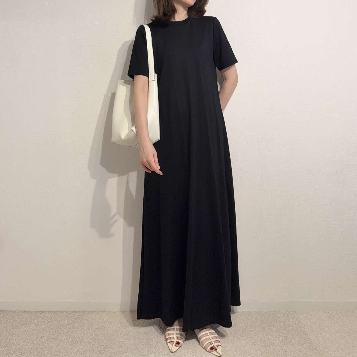 黒いワンピースに白いバッグとサンダルを合わせた女性の全身