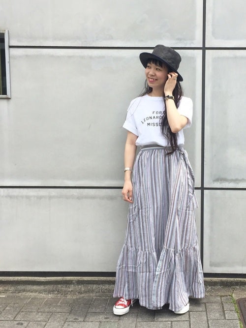 白のロゴTにストライプ模様のペプラムスカートを履いた女性