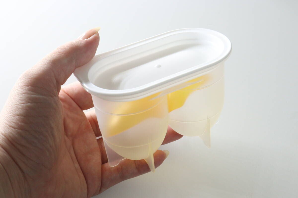 女性の手のひらに乗せたセリアの味玉名人容器とフタ 女性の手のひらに乗せたセリアの味玉名人容器とフタ