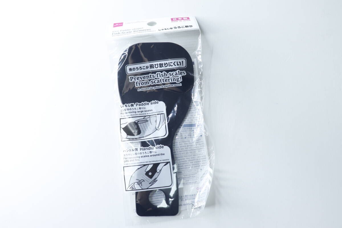 黒いしゃもじ型うろこ取りがパッケージに入っており、使用方法のイラストが見える