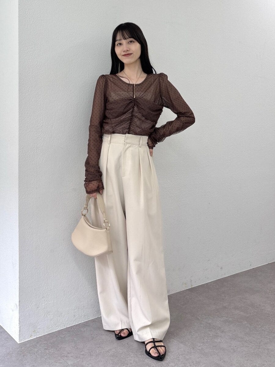 ブラウンのドット柄シアーブラウスとワイドパンツの女性