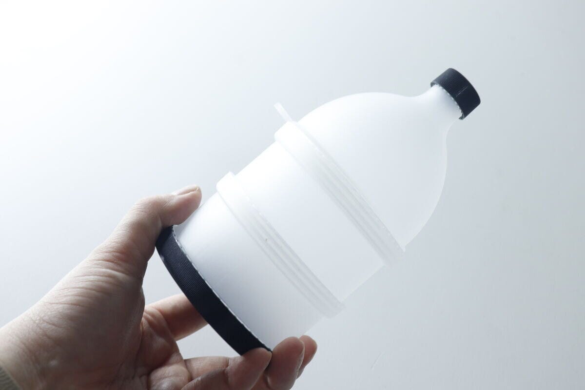 手が白いプロテイン容器を横向きに持ち、商品のサイズ感を示している 手が白いプロテイン容器を横向きに持ち、商品のサイズ感を示している