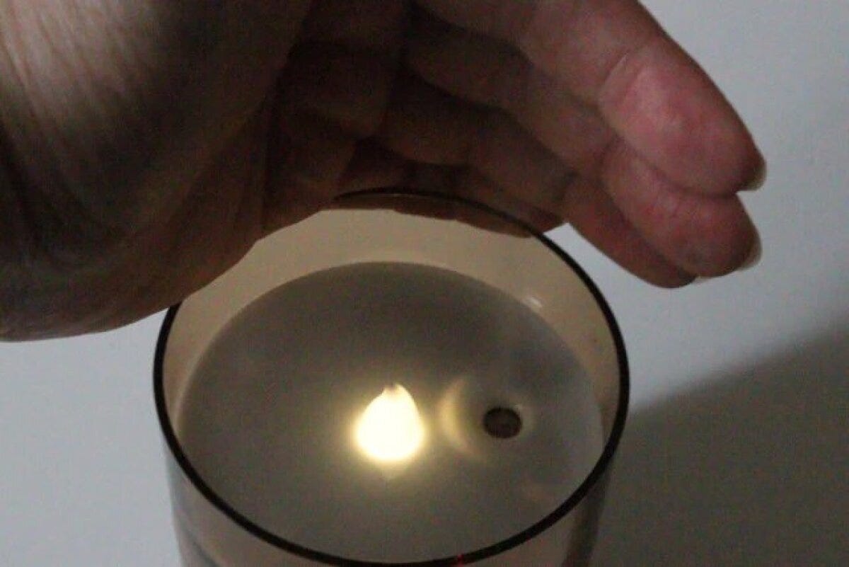 手がキャンドル型USB加湿器の蓋を開け、内部のライトが光っている様子