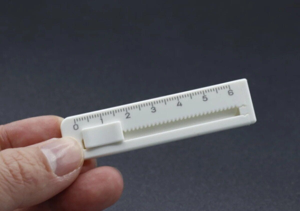 白いミニカッターを指でつまんで持っている様子 白いミニカッターを指でつまんで持っている様子