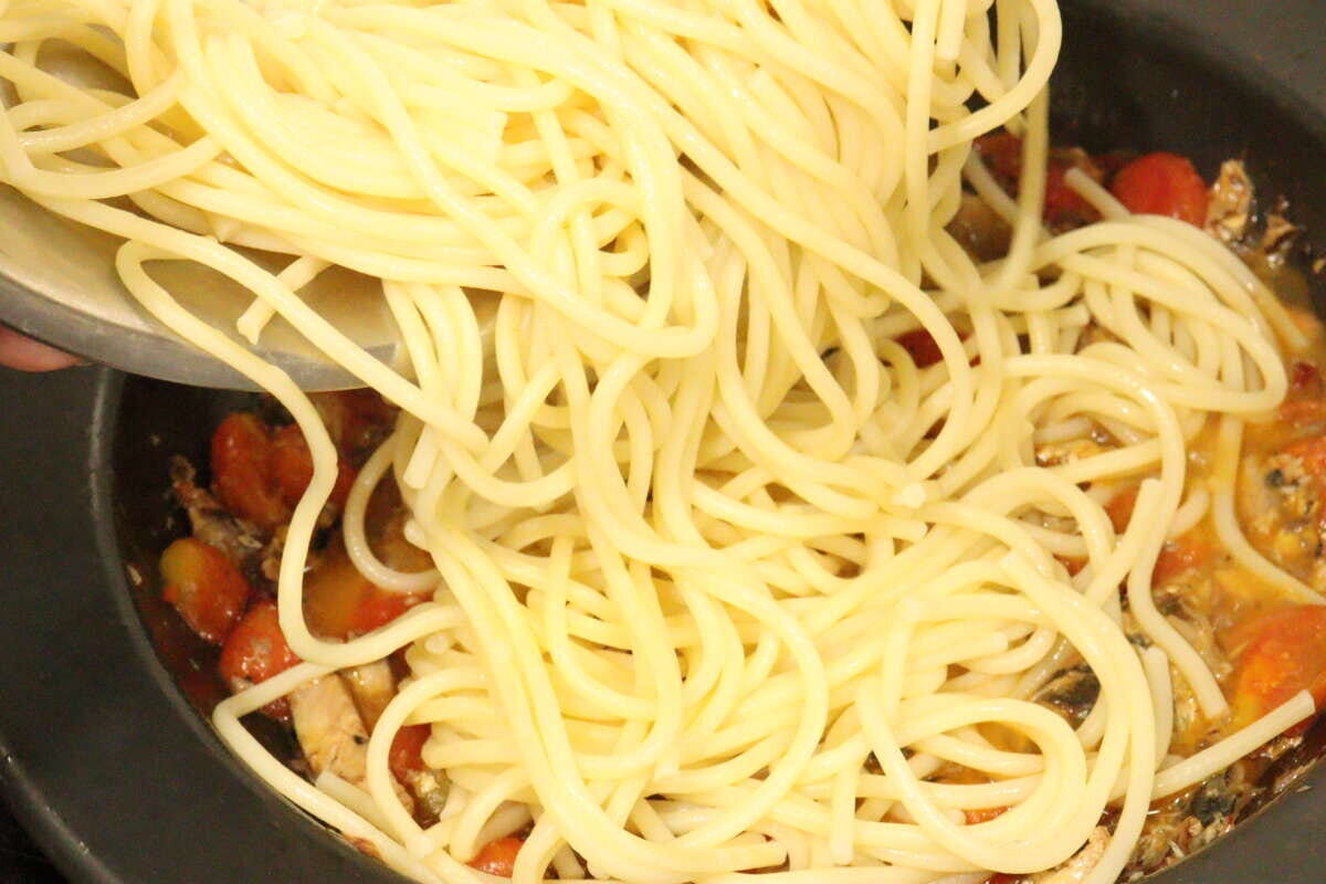 フライパンで煮込まれたソースの中に、茹で上がったパスタが投入され、絡めようとしている様子 フライパンで煮込まれたソースの中に、茹で上がったパスタが投入され、絡めようとしている様子