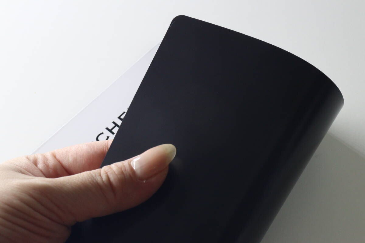 裏面が黒いマグネットになっているホワイトボードを手に持つ