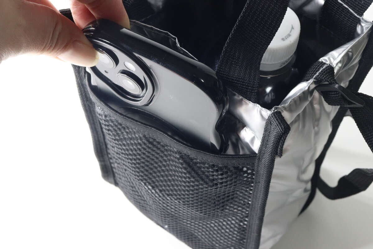 シルバーと黒のショルダーバッグのメッシュポケットにスマホを入れている手元