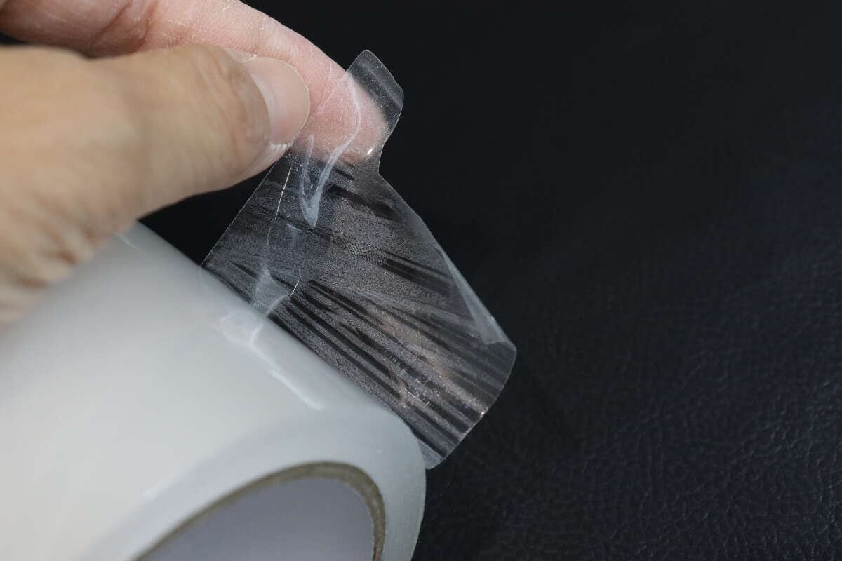 透明な梱包テープの端を指で剥がしているアップ 透明な梱包テープの端を指で剥がしているアップ