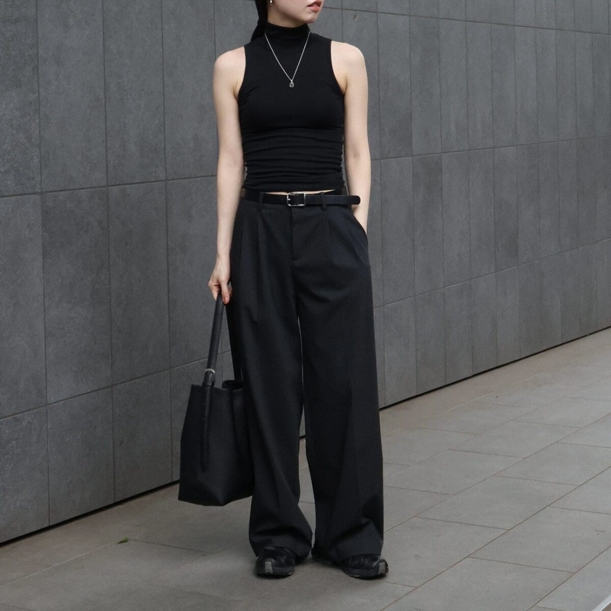 黒いノースリーブとワイドパンツを着用し、バッグを持つ女性の全身 黒いノースリーブとワイドパンツを着用し、バッグを持つ女性の全身