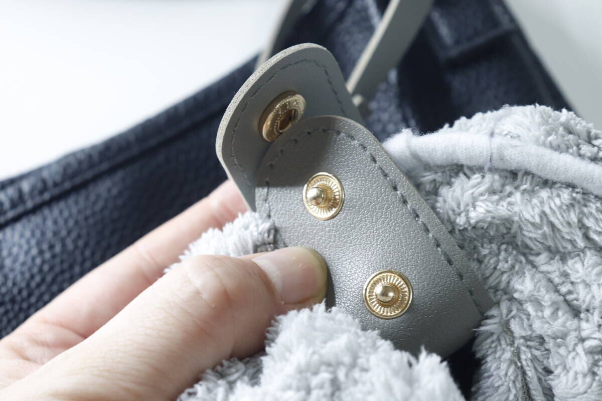 タオルホルダーのスナップボタンでグレーのタオルを固定する手元