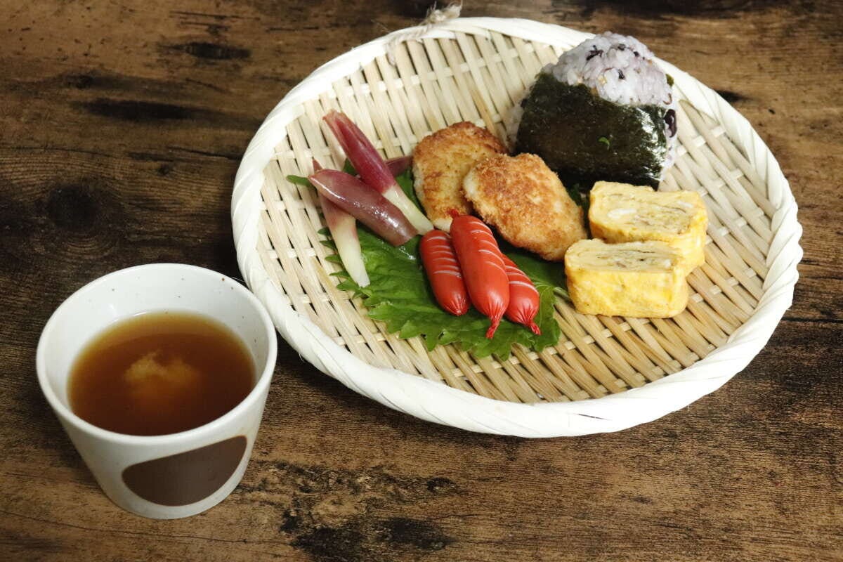 盆ざるに、おにぎり、卵焼き、ウインナーが盛り付けられたワンプレート 盆ざるに、おにぎり、卵焼き、ウインナーが盛り付けられたワンプレート