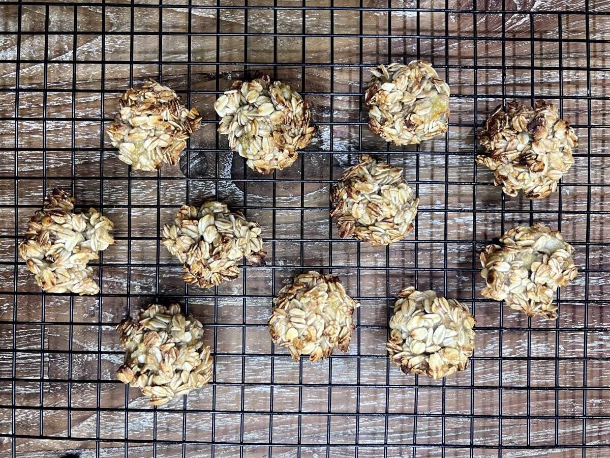 黒いケーキクーラーの上に、こんがりと焼き上がったオートミールクッキーが10個並べられている 黒いケーキクーラーの上に、こんがりと焼き上がったオートミールクッキーが10個並べられている