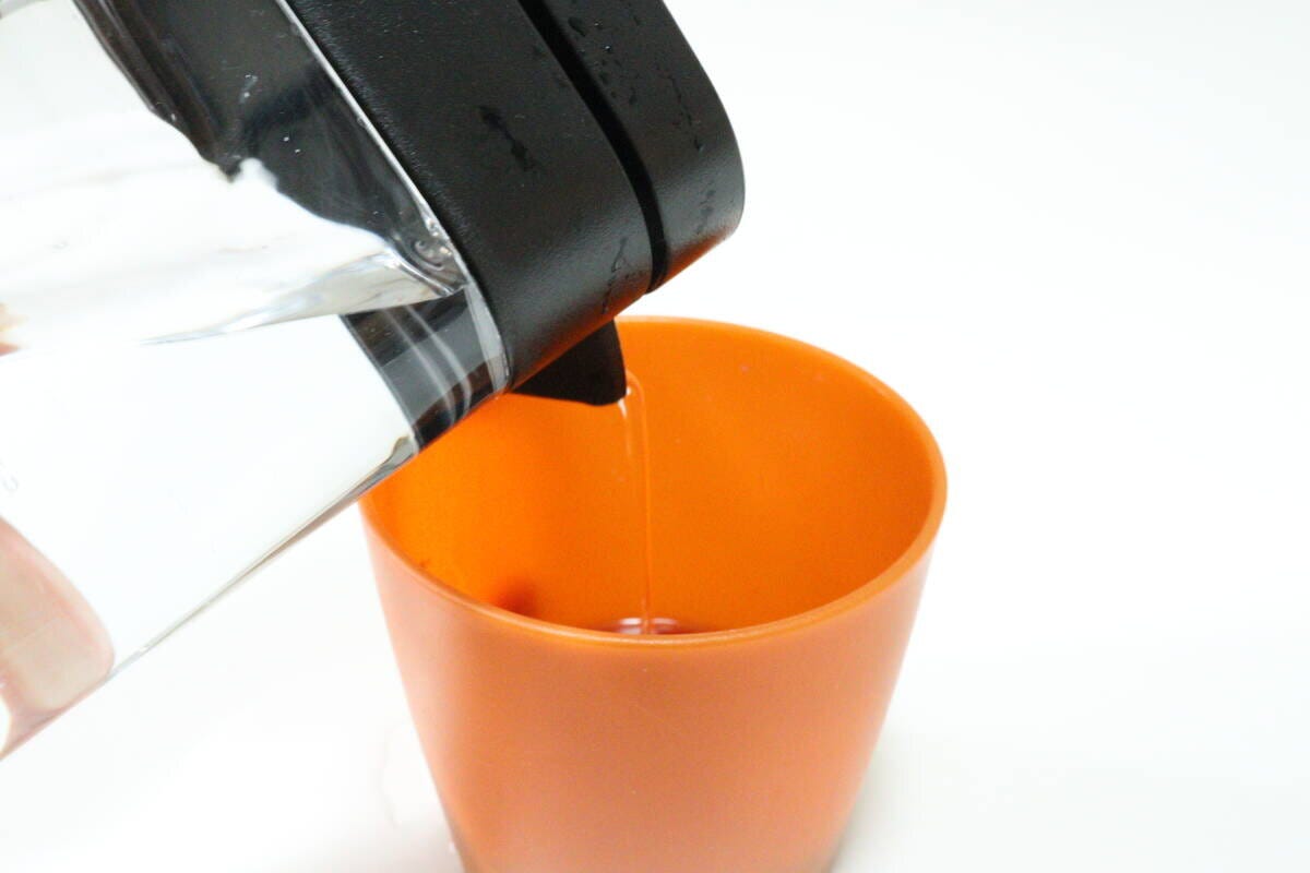 ダイソー 横置きできる冷水筒(取っ手なし、1.6L、ブラック) ダイソーの横置きできる冷水筒(取っ手なし、1.6L、ブラック)で飲み物を注ぐ