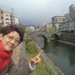 長崎の眼鏡橋の前で丸眼鏡をかけて（提供写真）