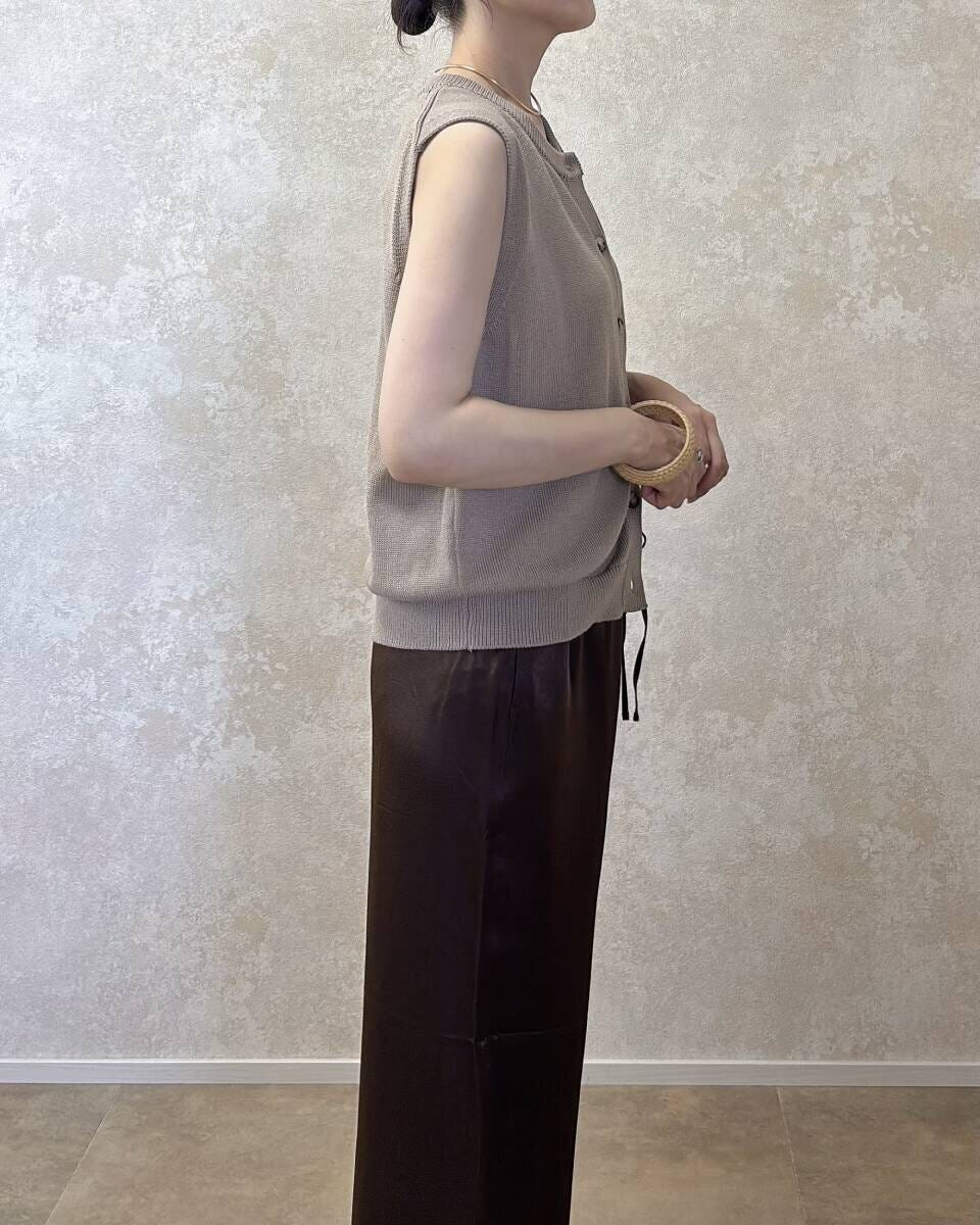 ベージュニットとブラウンパンツの女性が横向きに立つ ベージュニットとブラウンパンツの女性が横向きに立つ