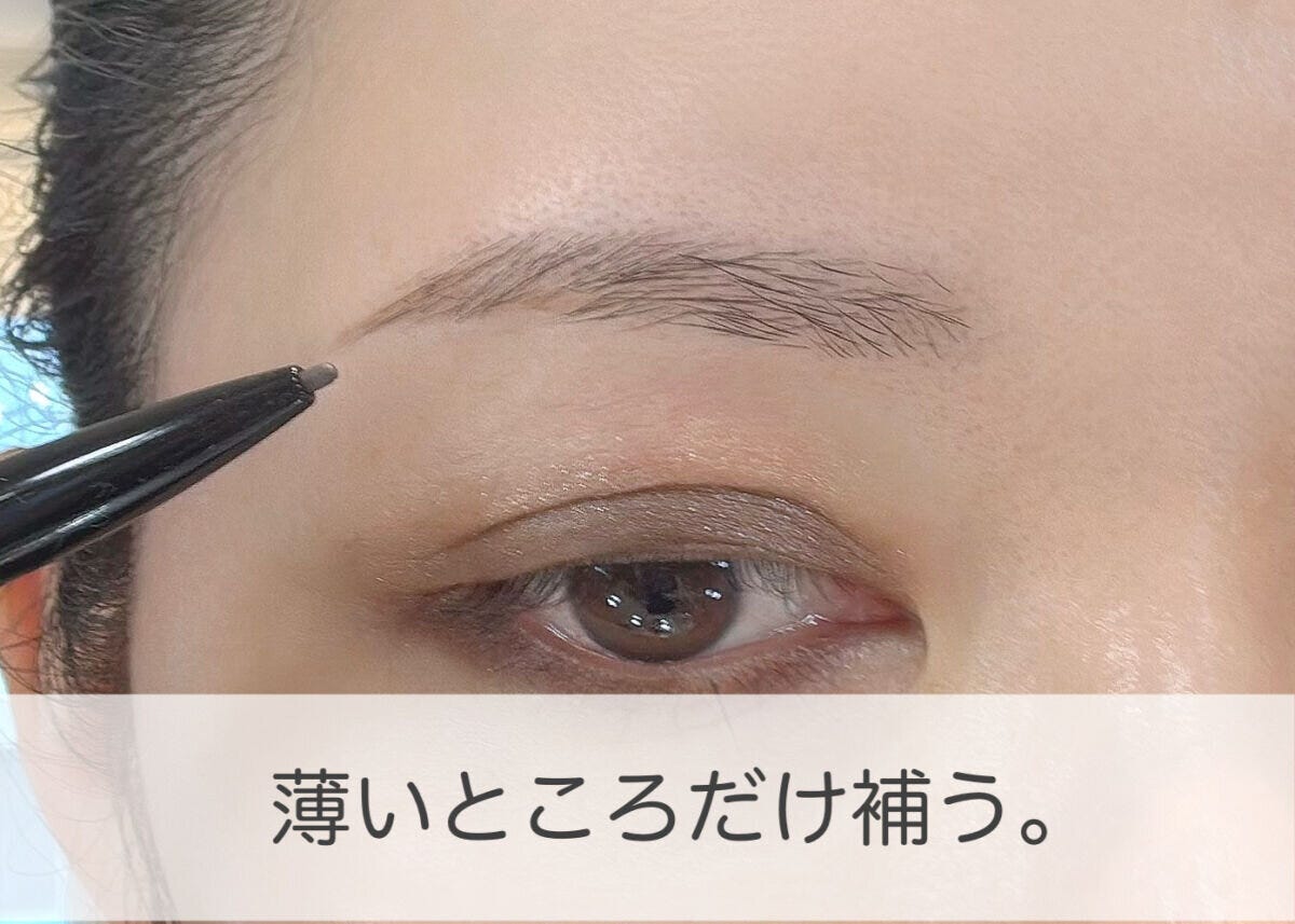 眉ペンシルで眉の薄い部分に一本ずつ毛を描き足す女性の手元