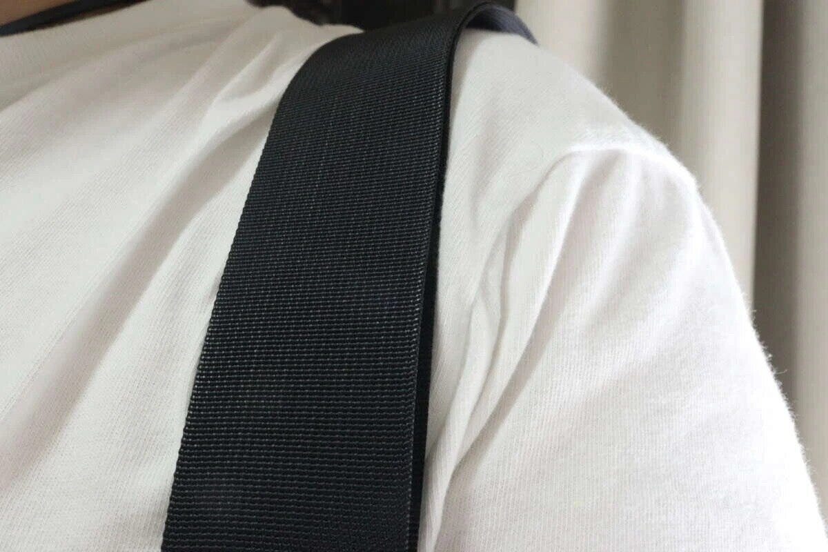 白いTシャツを着た人の肩に黒いショルダーバッグストラップがかかっている 白いTシャツを着た人の肩に黒いショルダーバッグストラップがかかっている