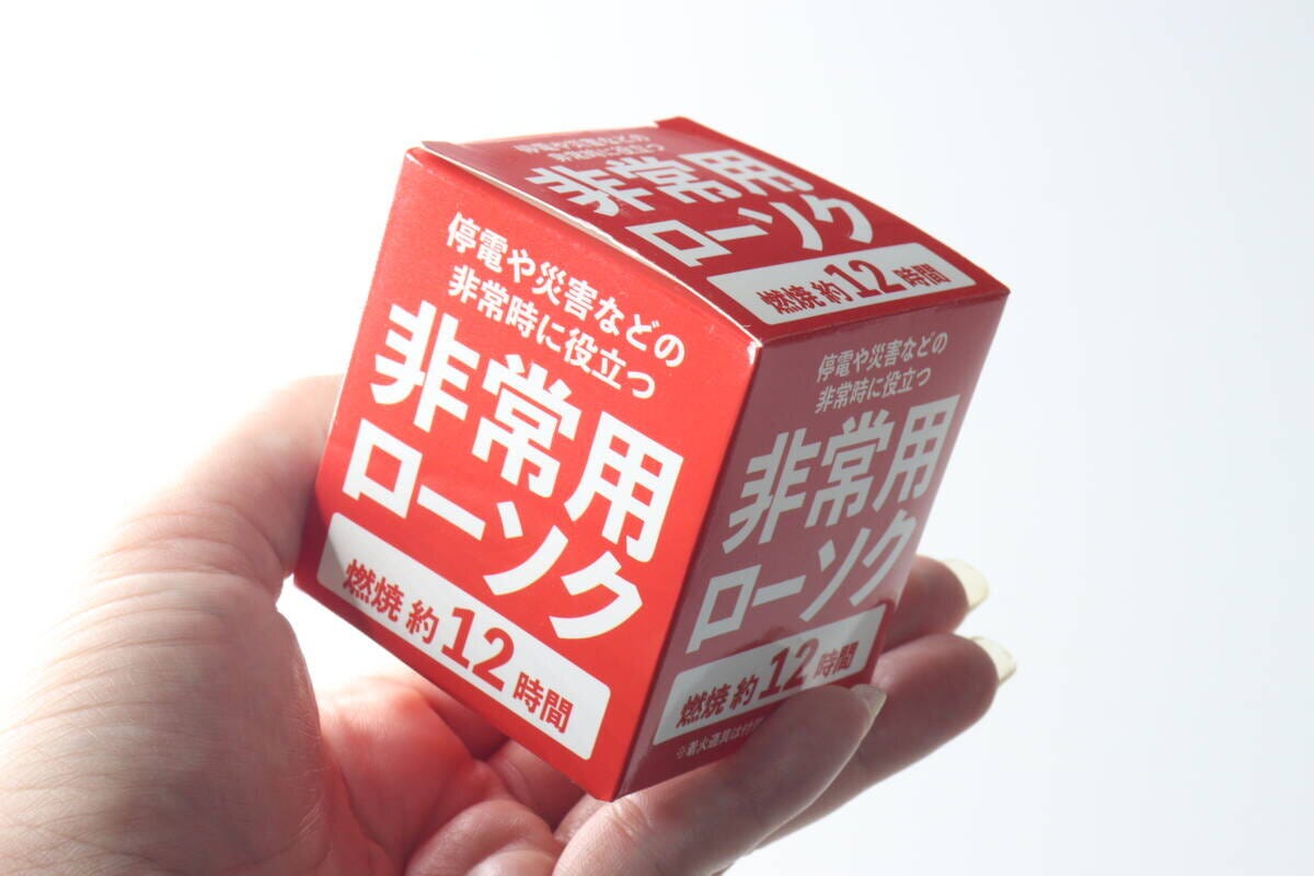 女性が赤い箱の非常用ローソクを持っている 女性が赤い箱の非常用ローソクを持っている