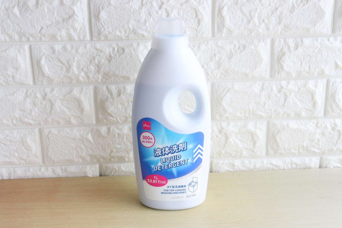 白いレンガ調の壁を背景に、白いボトルに入ったダイソーの液体洗剤が置かれている