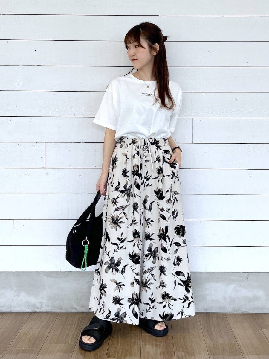 白Tシャツとボタニカル柄ワイドパンツの女性