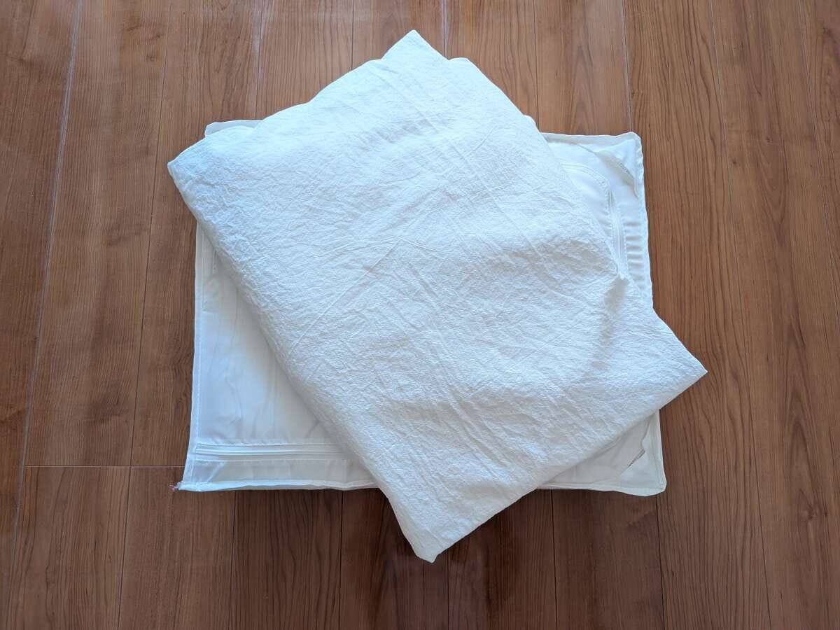 木目の床に置かれた白いシーツや寝具を片付けのため取り出した俯瞰写真