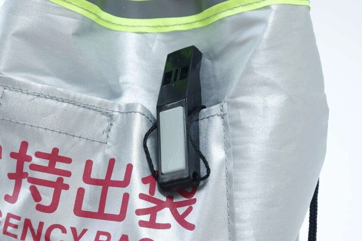 銀色のリュックのポケットに黒いホイッスルがクリップで留められている 銀色のリュックのポケットに黒いホイッスルがクリップで留められている