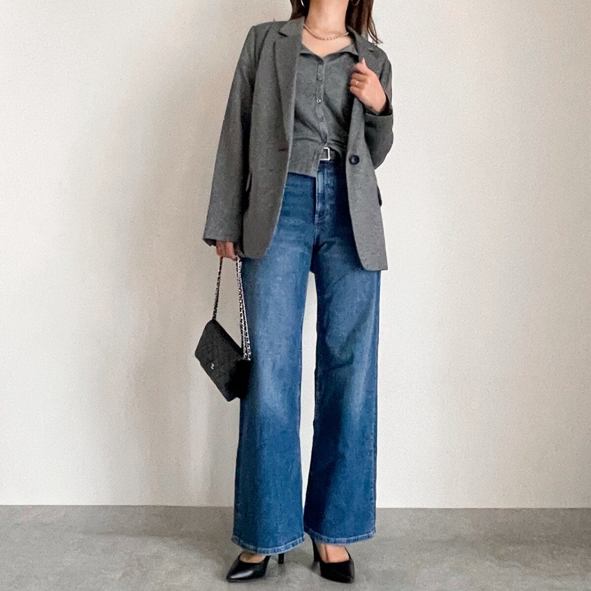 グレーのカーディガンをジャケットインしデニムを合わせた女性