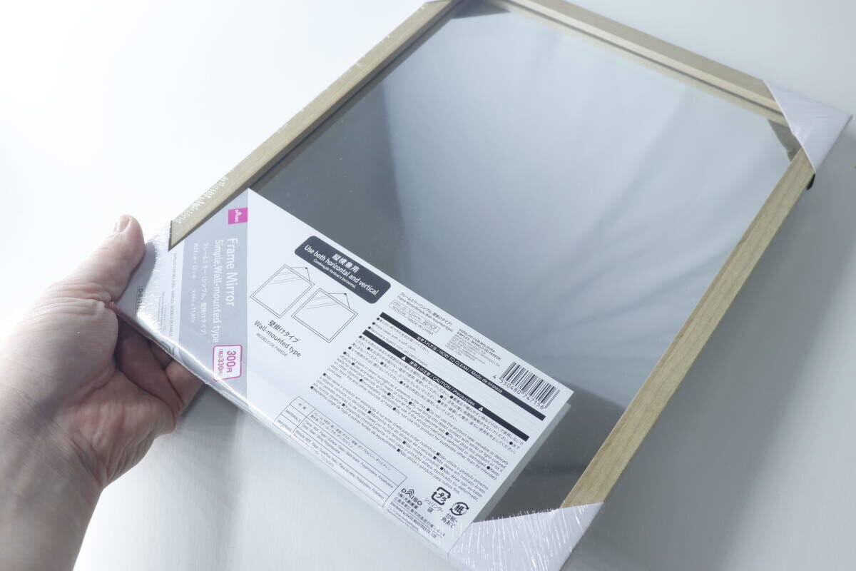 手で持ったダイソーの壁掛けミラーのパッケージ