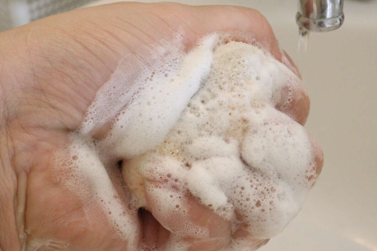 洗顔料をつけたひょうたん型の洗顔パフを手のひらで揉み泡立てている