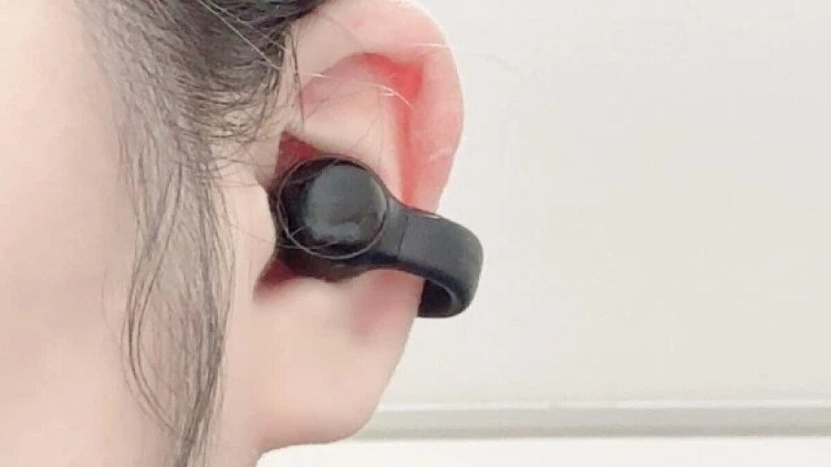 女性の耳に装着された、耳穴を挟むタイプの黒いワイヤレスイヤホン 女性の耳に装着された、耳穴を挟むタイプの黒いワイヤレスイヤホン