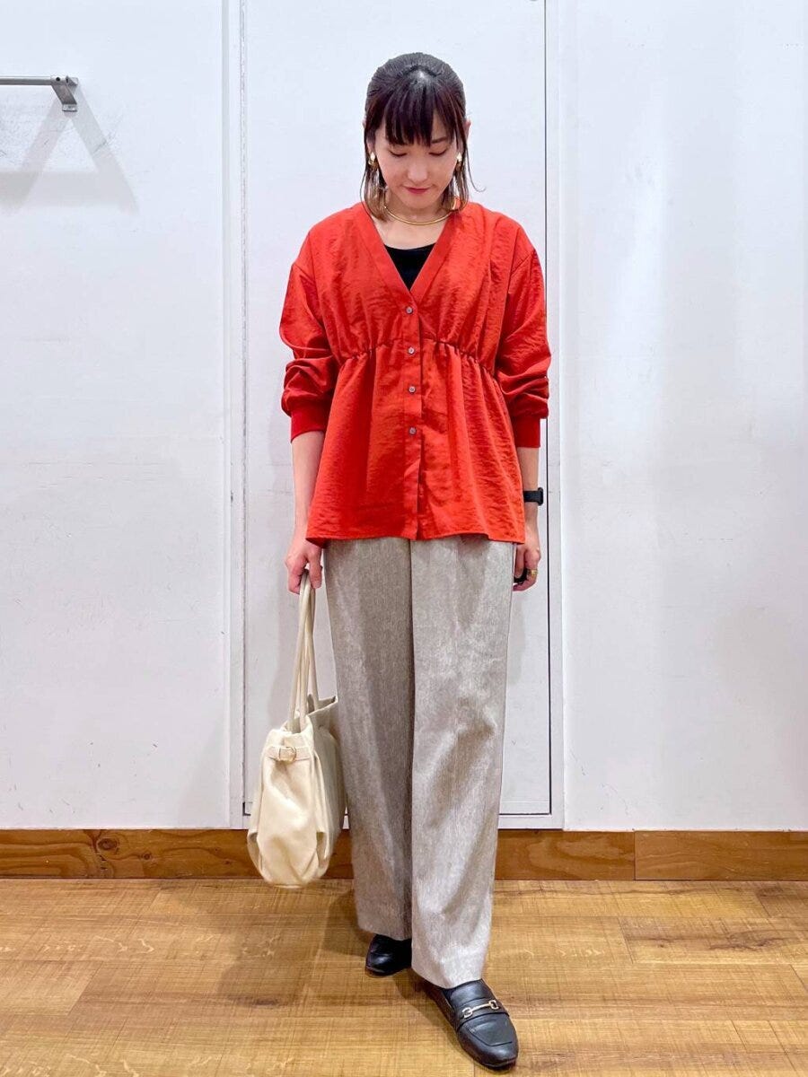 オレンジのペプラムカーディガンとワイドパンツを合わせた女性