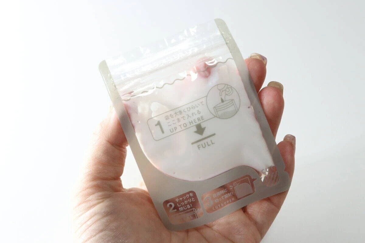 女性の手のひらに乗せた乳白色の詰め替えパウチ