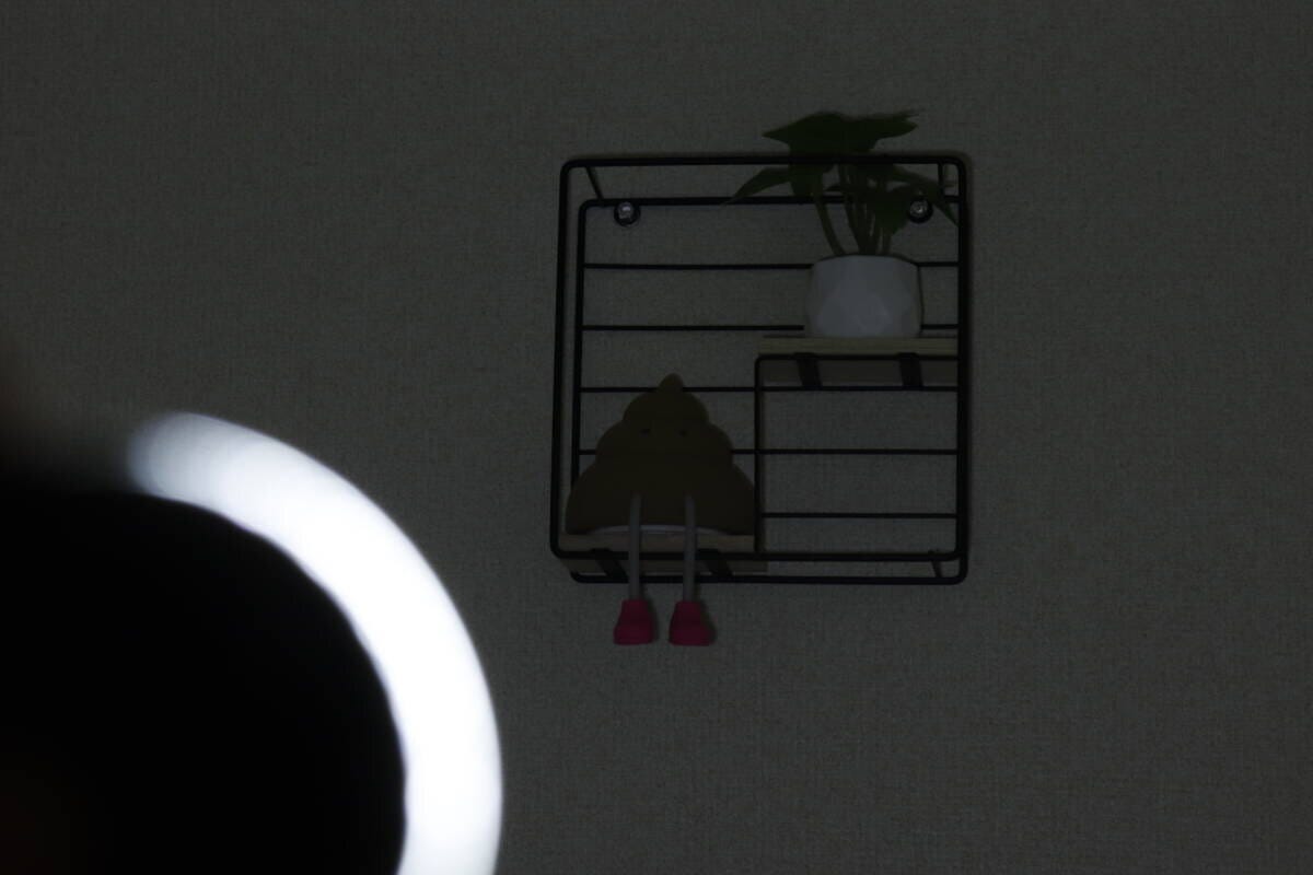 暗い部屋でライトのCOBモードLowを壁の棚に当てて薄暗く照らしている