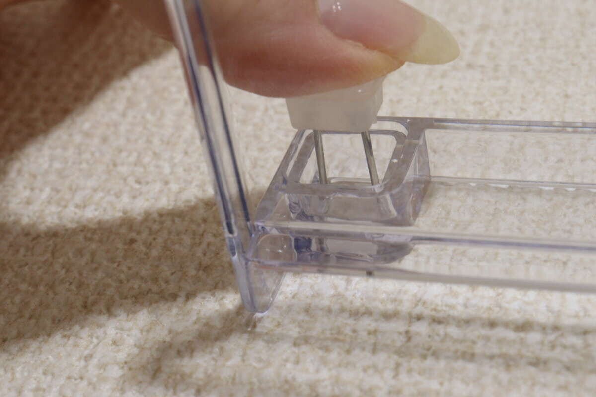 棚の穴に専用ピンを差し込み指で押し込んで取り付けている手元の様子 棚の穴に専用ピンを差し込み指で押し込んで取り付けている手元の様子