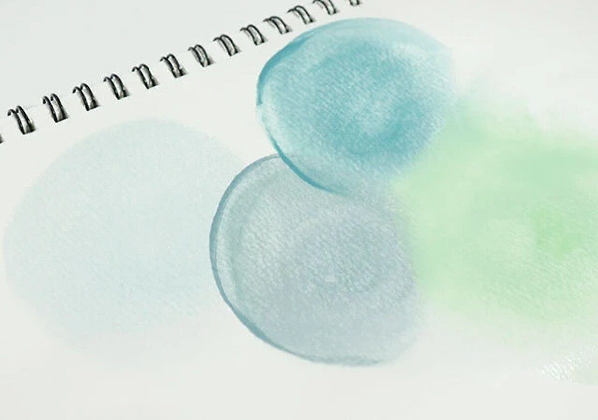ノートに水彩絵の具でくすみカラーの丸やグラデーションが描かれている ノートに水彩絵の具でくすみカラーの丸やグラデーションが描かれている