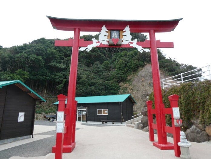 元乃隅神社の境内入口にある朱塗りの大鳥居。賽銭箱は大鳥居の上、2匹の白狐が向き合った所にあります(2022年3月撮影)