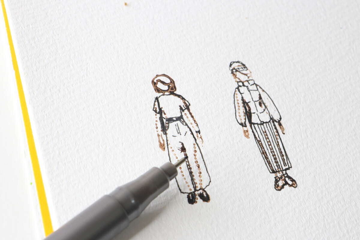 押したスタンプの上からペンで服のイラストを書き込んでいる様子