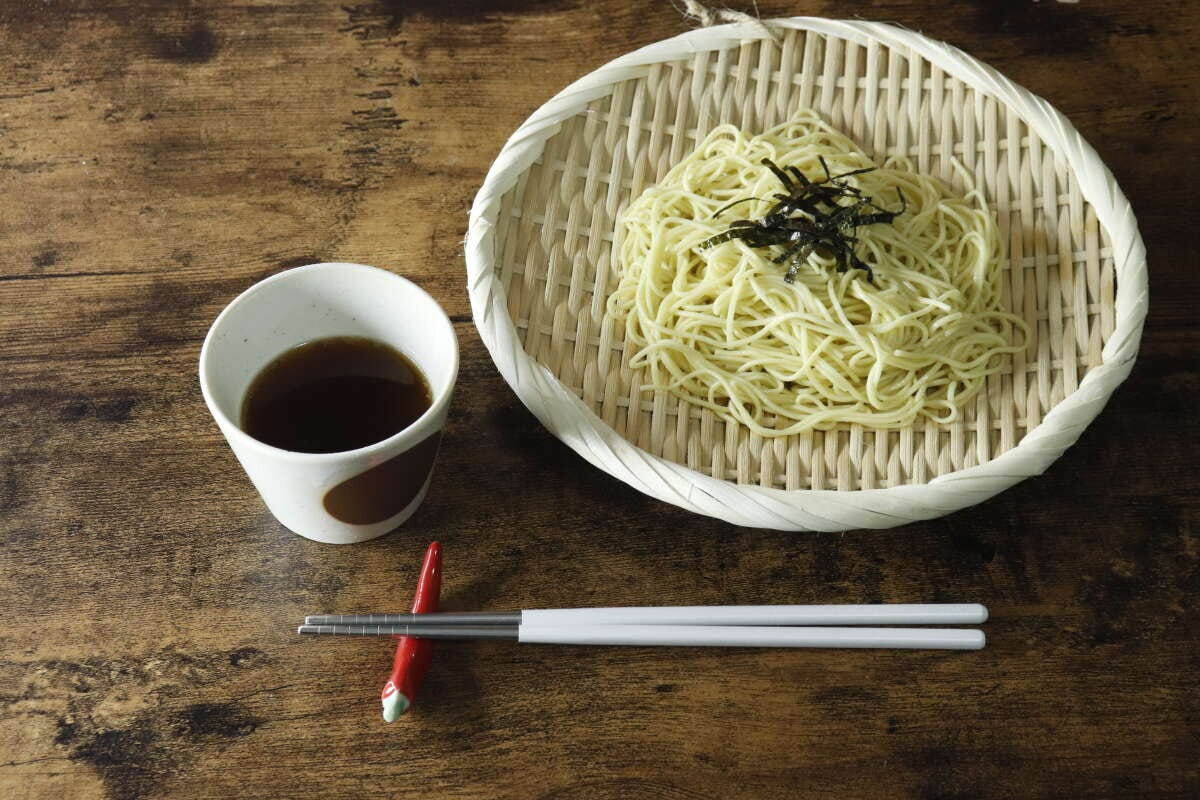 盆ざるに盛り付けられた冷やし中華と、つゆ、箸が並ぶ食卓 盆ざるに盛り付けられた冷やし中華と、つゆ、箸が並ぶ食卓