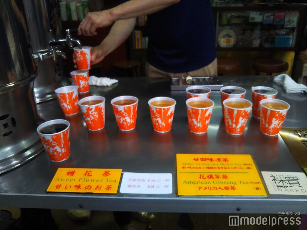 大きなタンクから温かい涼茶がカップに並々と注がれます。お店の人に10＄を手渡して、好みの涼茶を受け取る／提供画像