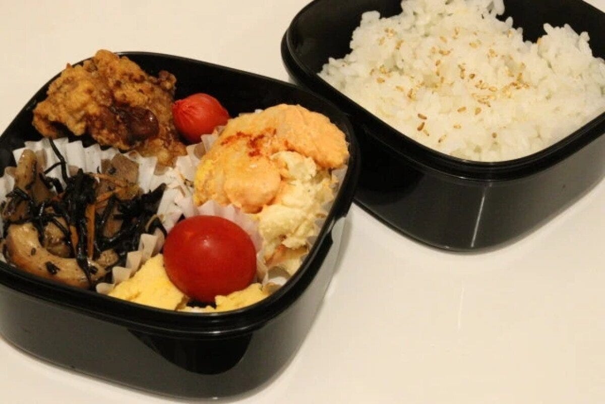 黒い二段弁当箱におかずとご飯が美味しそうに詰められている 黒い二段弁当箱におかずとご飯が美味しそうに詰められている