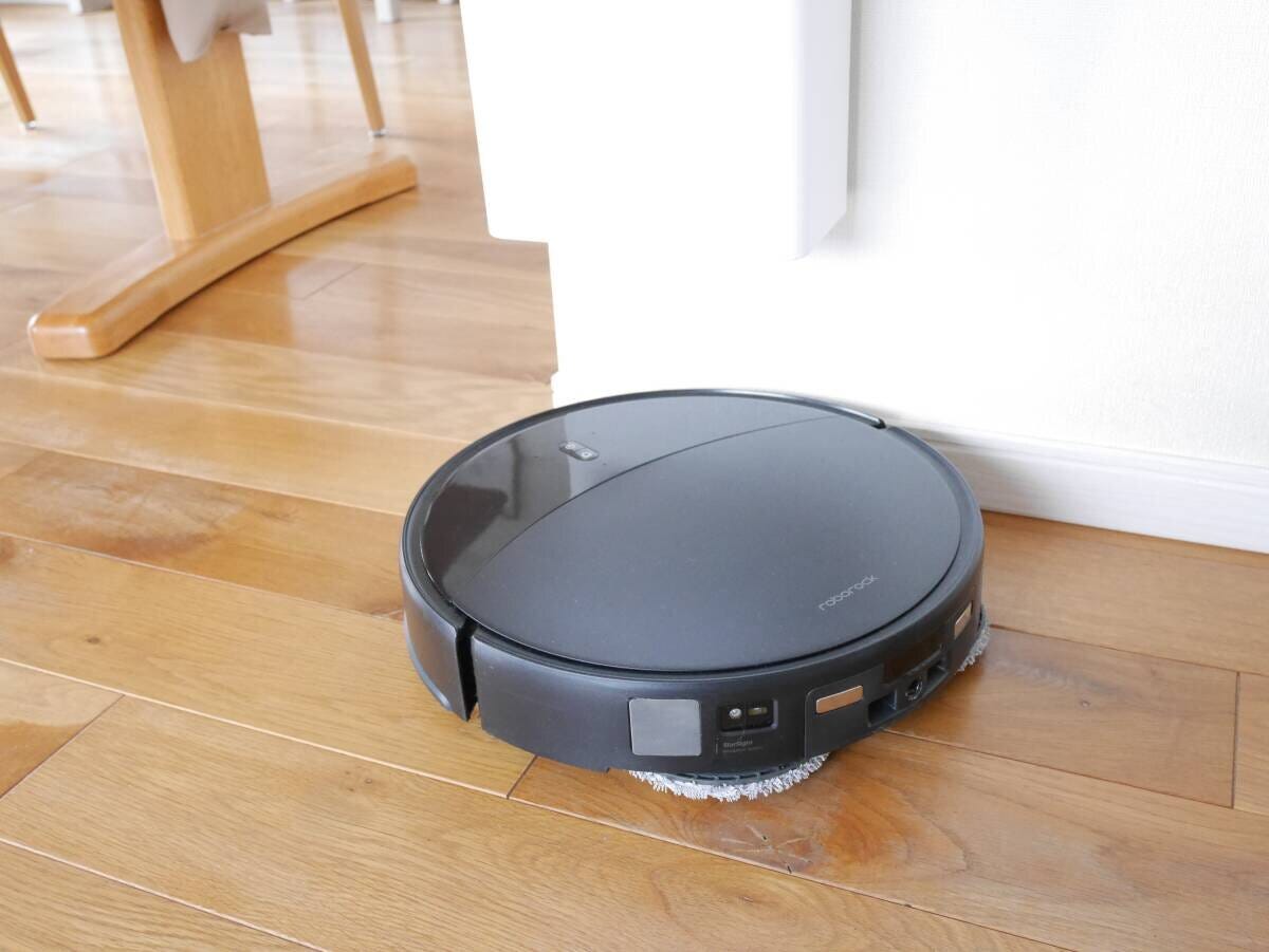 壁掛けゴミ箱の下を黒いロボット掃除機がスムーズに通過している様子 壁掛けゴミ箱の下を黒いロボット掃除機がスムーズに通過している様子