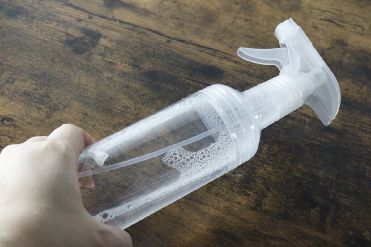 液体が入った透明なスプレー容器を片手で持っている