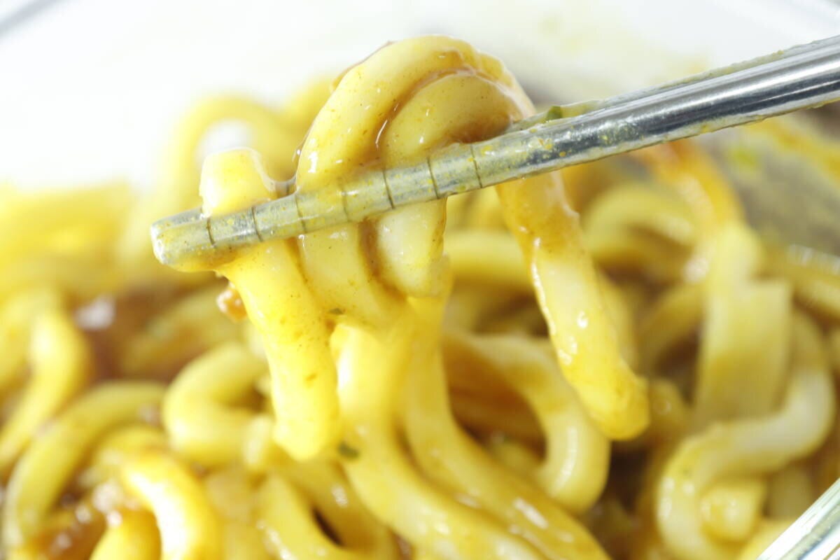 箸でカレーうどんの麺をすくい上げ、とろみのあるスープが絡んでいる 箸でカレーうどんの麺をすくい上げ、とろみのあるスープが絡んでいる