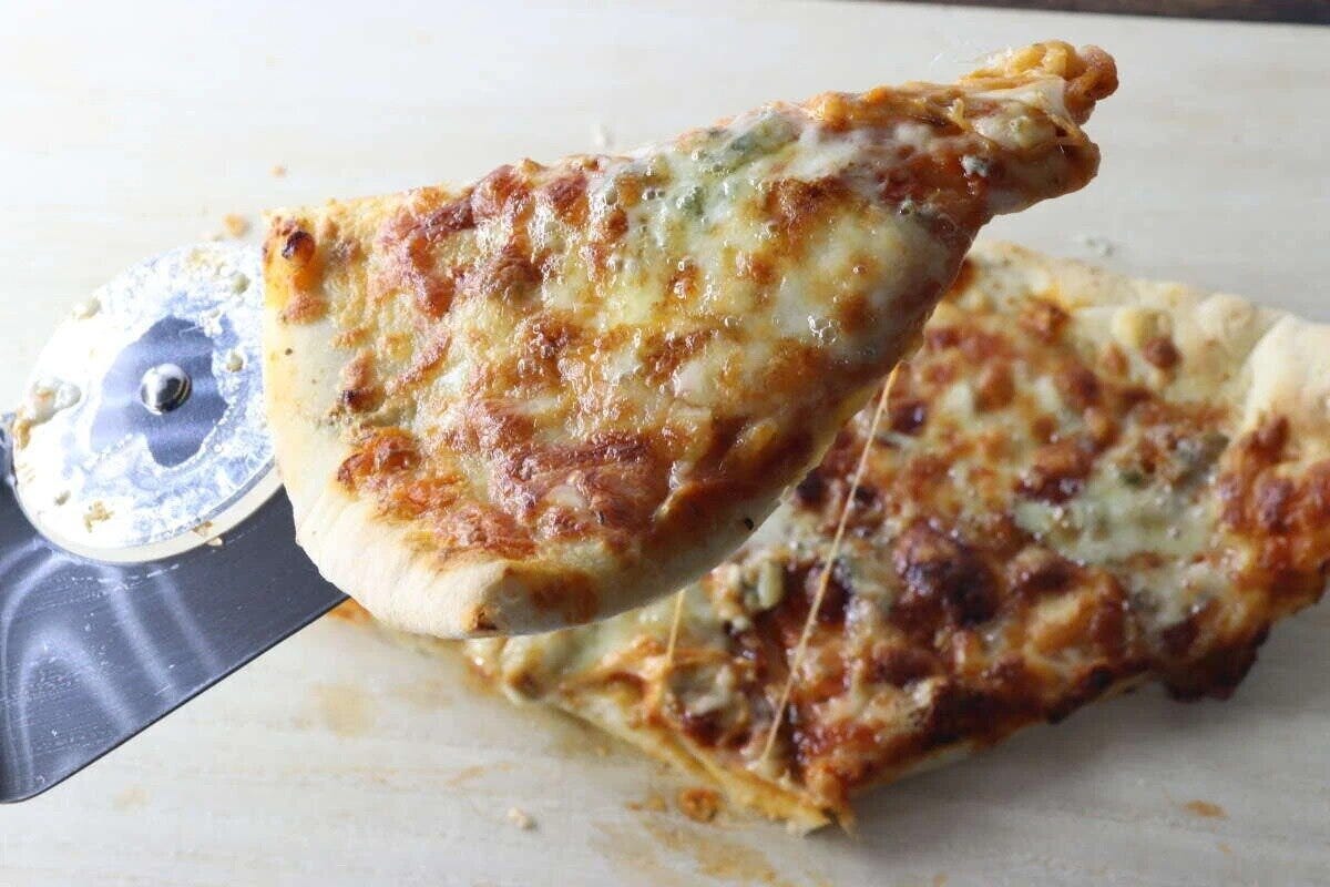 ピザサーバーでカットしたチーズたっぷりのピザをすくい上げている。
