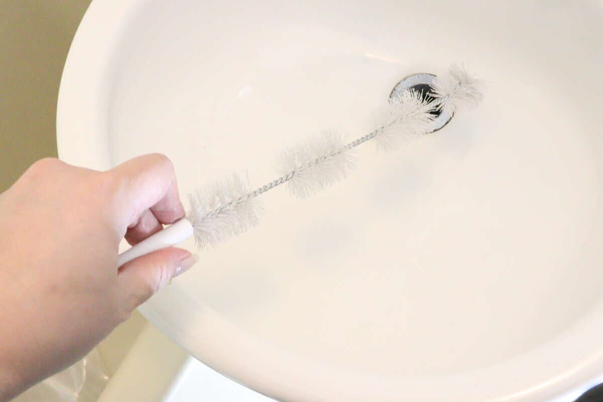 女性が洗面台の排水口に4連パイプクリーナーを差し込んでいる
