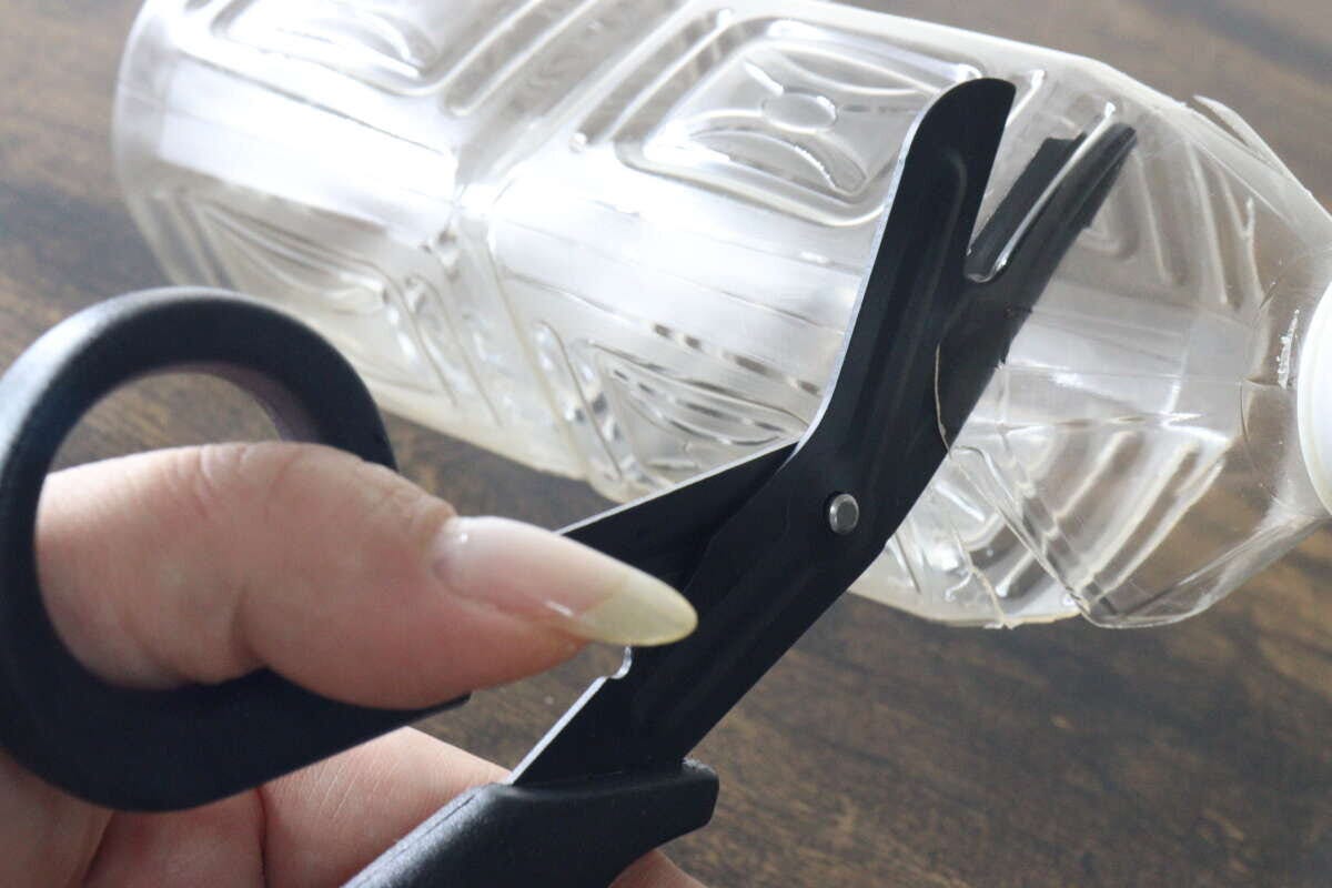 固いプラスチック製のペットボトルを黒いハサミで難なくカットしている場面 固いプラスチック製のペットボトルを黒いハサミで難なくカットしている場面