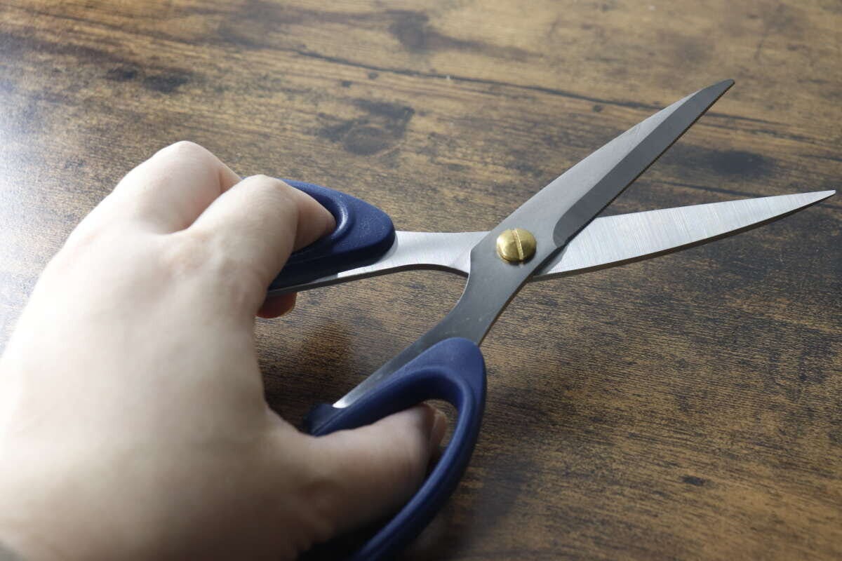 女性がネイビーの厚刃キッチンハサミを広げて持っている手元