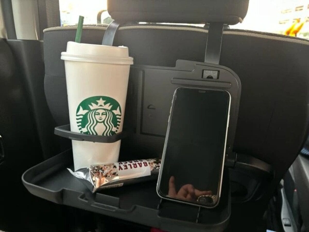 後部座席のリアシートトレイに飲み物とお菓子、スマホが置かれている 後部座席のリアシートトレイに飲み物とお菓子、スマホが置かれている