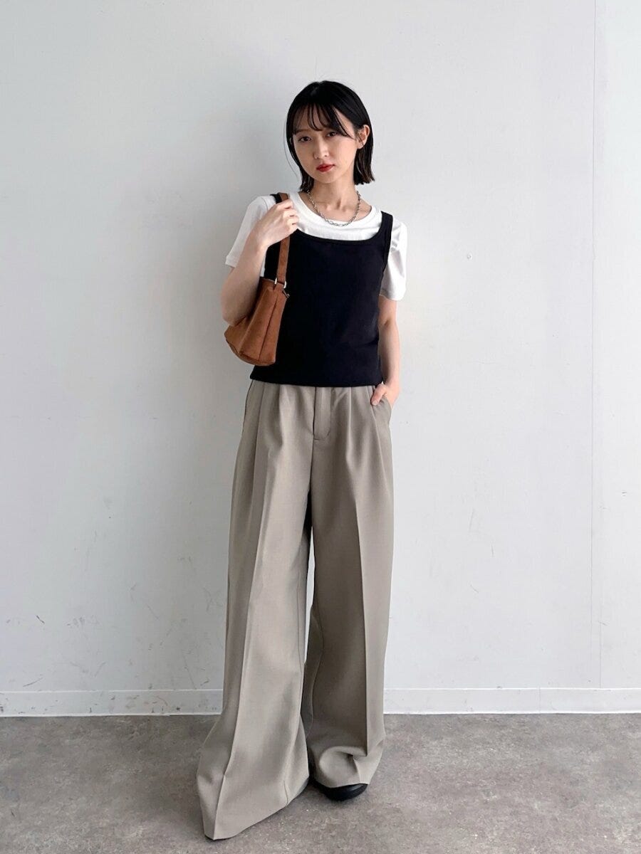白Tに黒タンクトップを重ね、ベージュワイドパンツと茶バッグの女性 白Tに黒タンクトップを重ね、ベージュワイドパンツと茶バッグの女性