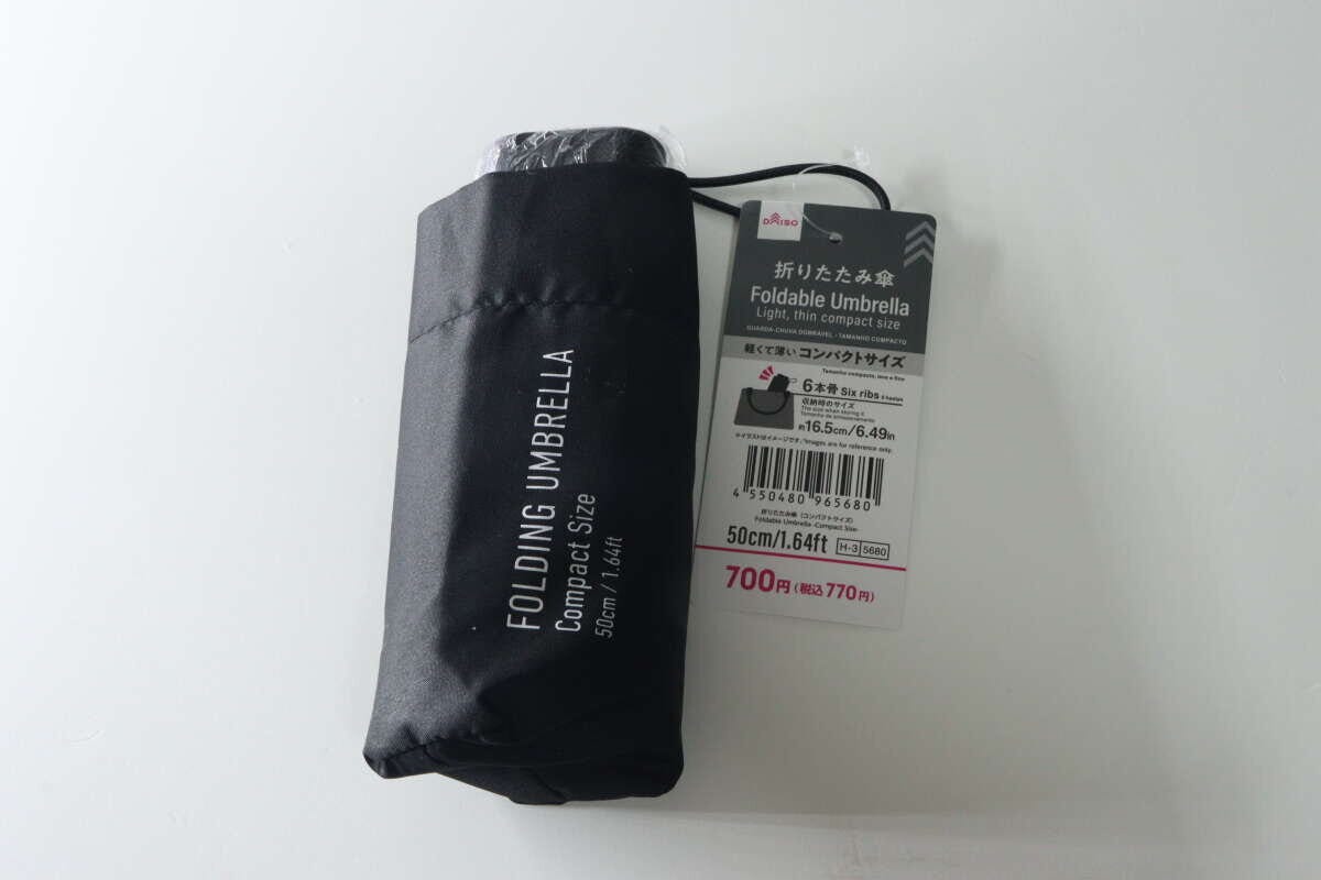 黒い折りたたみ傘がパッケージに入っており、商品名と770円の価格が見える